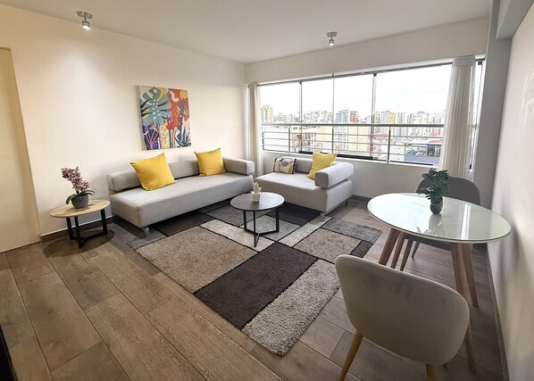 A modern living room with a sofa, two armchairs, a coffee table, a small side table, and a dining table. - Aparts4Days Miraflores Down Town 1 or 3 Bedroom Apartment (Lima)