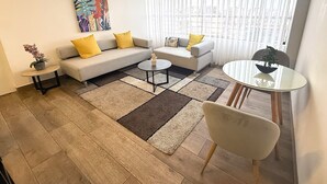 A modern living room with a sofa, two armchairs, a coffee table, and a dining table. - Aparts4Days Miraflores Down Town 1 or 3 Bedroom Apartment (Lima)