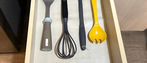 A drawer with kitchen utensils including a spatula, whisk, and ladle.