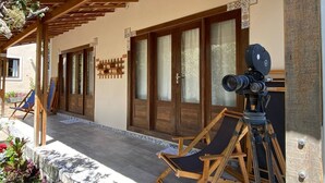 Un espacio al aire libre techado con sillas de madera y una cámara sobre un trípode.