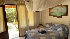 Un dormitorio con cama, mesita de noche, un cuadro y vista al exterior.
