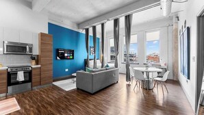 A modern apartment with a kitchen, dining area, and living room. - Skyline View 3BR Loft | Pool + Valet Parking (Dallas)