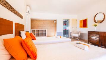 A hotel room with two beds, a wooden headboard, a wooden cabinet, a mirror, and a window.