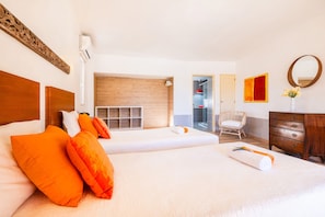 Ett hotellrum med två sängar, en sänggavel i trä, ett träskåp, en spegel och ett fönster.