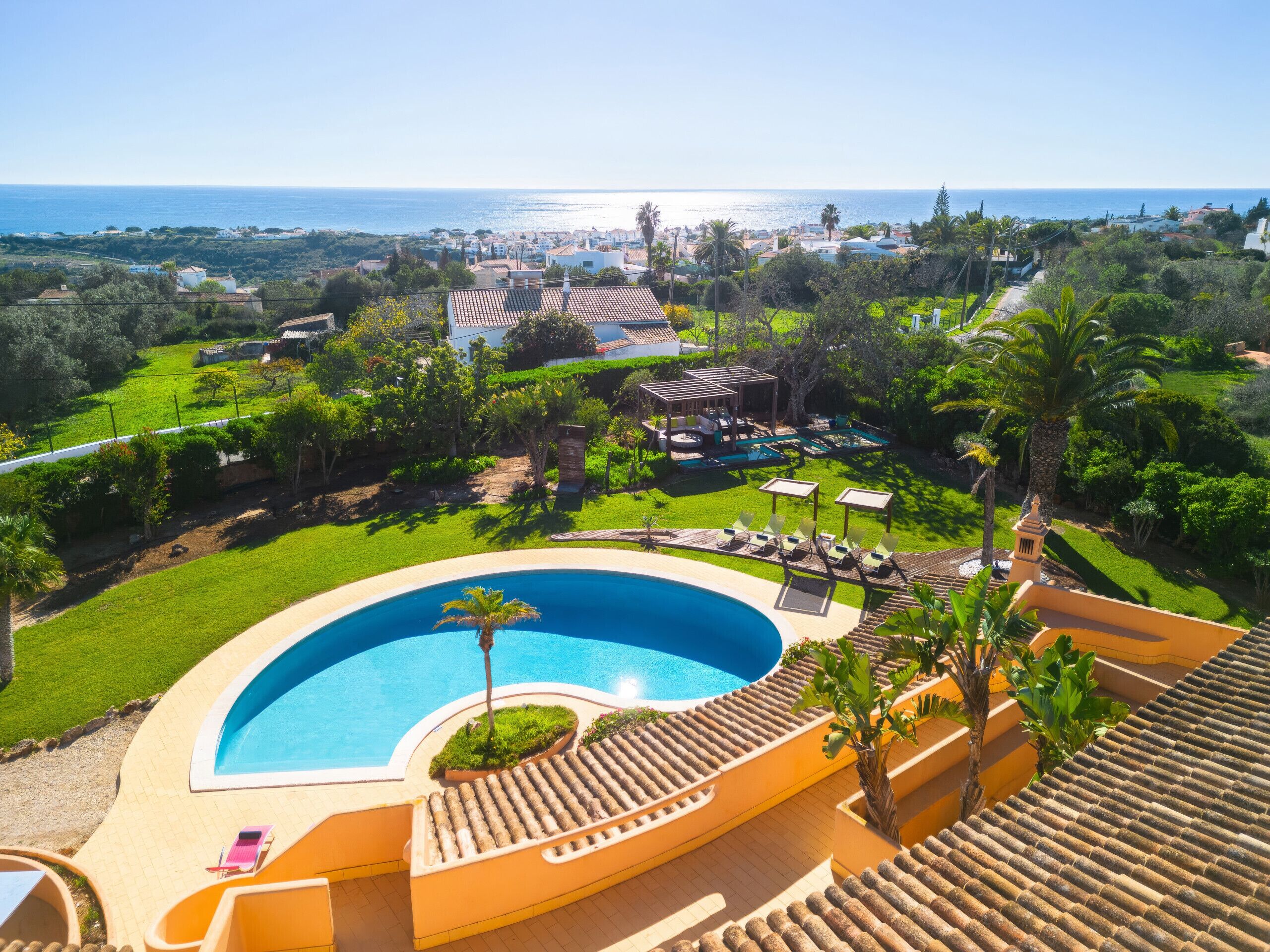A resort with a large swimming pool, lounge chairs, and a view of the ocean.