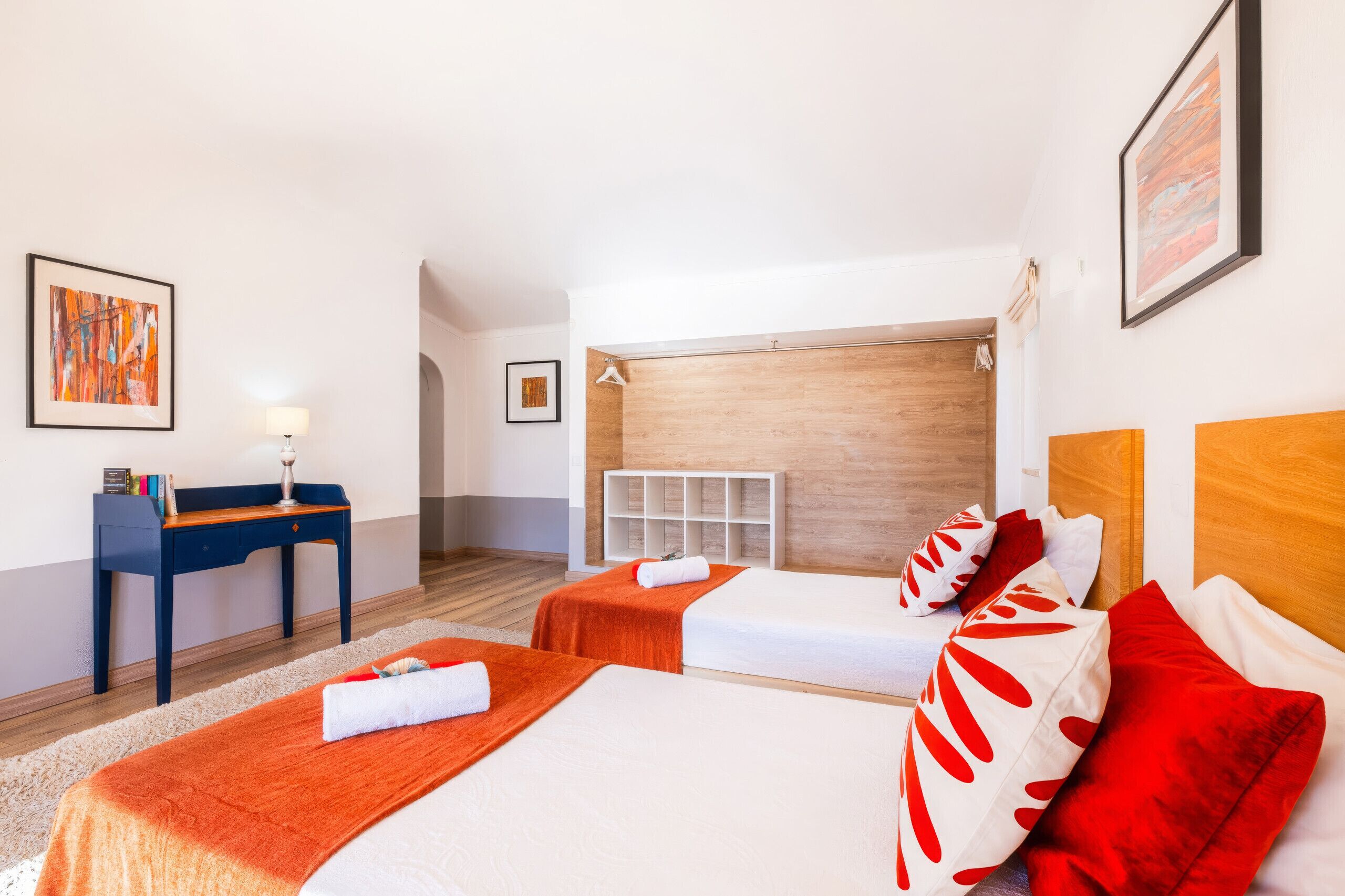 Ett hotellrum med två sängar, ett skrivbord, en stol och ett litet bord.