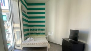 Makuuhuoneessa on sänky, lipasto, televisio ja ikkuna.