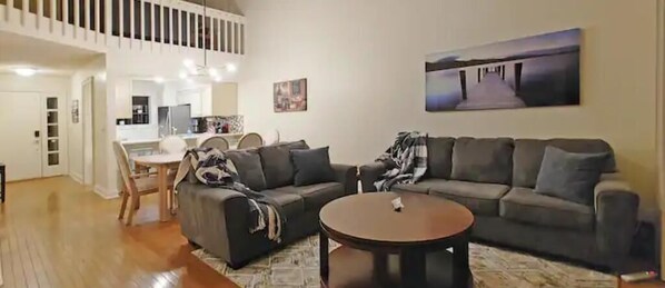 Relax in this stylish living area with a mezzanine level, featuring a large sofa, coffee table, and dining table.