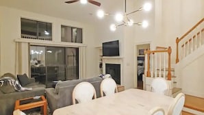 A spacious living room with a fireplace, a dining area, and a staircase.