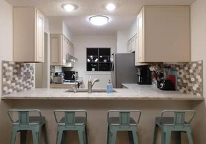 Una cocina con una isla central, taburetes de bar y una ventana sobre el fregadero.