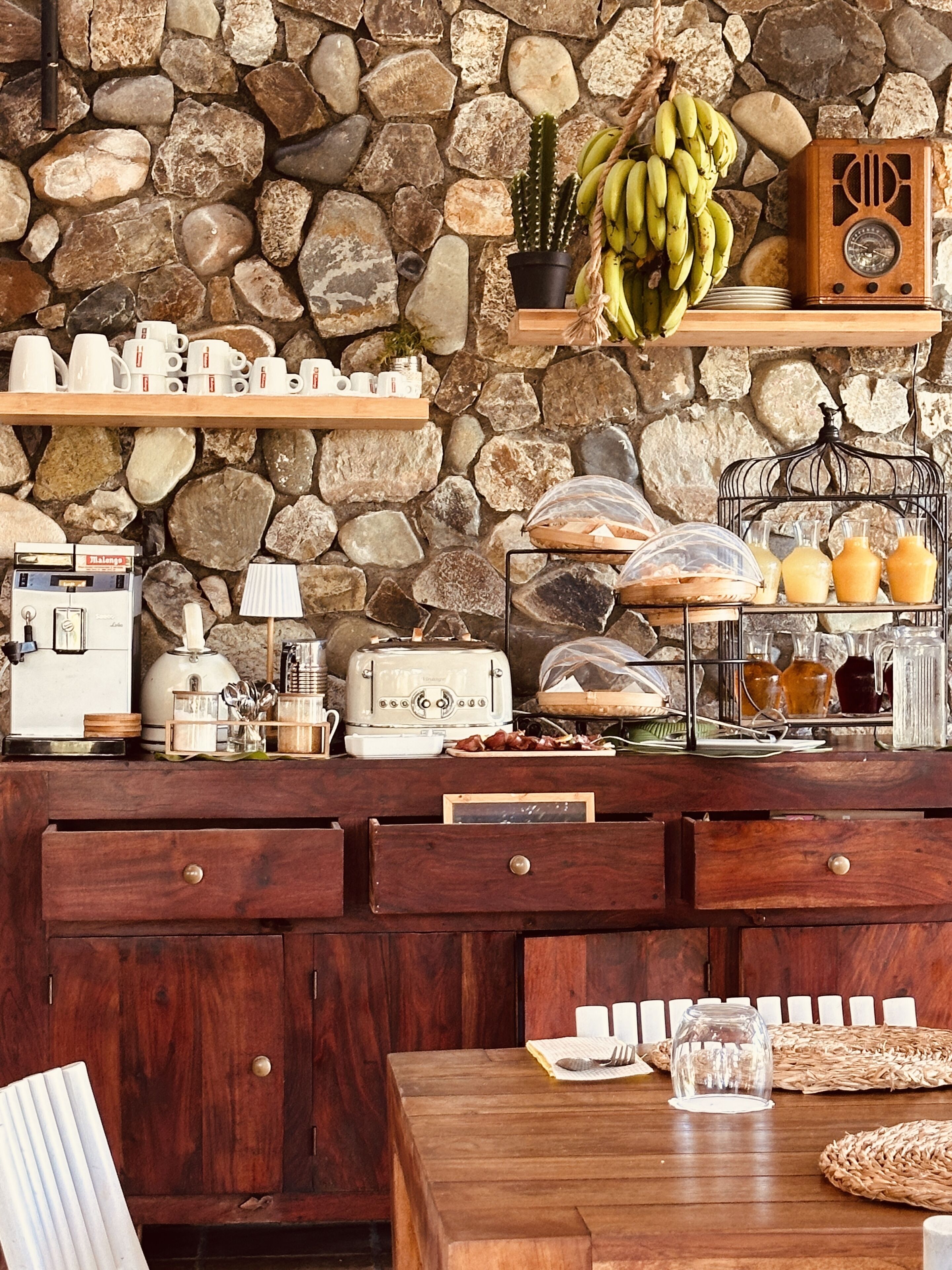A kitchen with a stone wall, wooden cabinets, and various appliances.