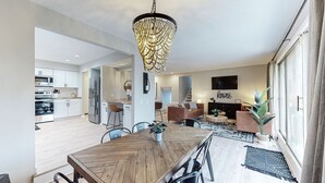 A modern kitchen with white cabinets, stainless steel appliances, and a wooden dining table with chairs.