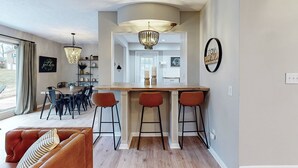 A modern kitchen with a bar area, wooden flooring, and pendant lighting.