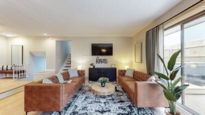 A modern living room with two brown sofas, a coffee table, and a TV mounted on the wall.