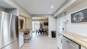 A modern kitchen with a wooden countertop, stainless steel appliances, and a dining area with a chandelier.