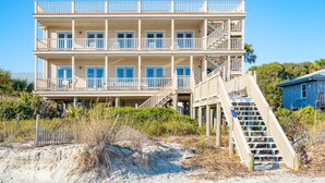 A multi-story beachfront hotel with balconies, a staircase, and a lifeguard tower.