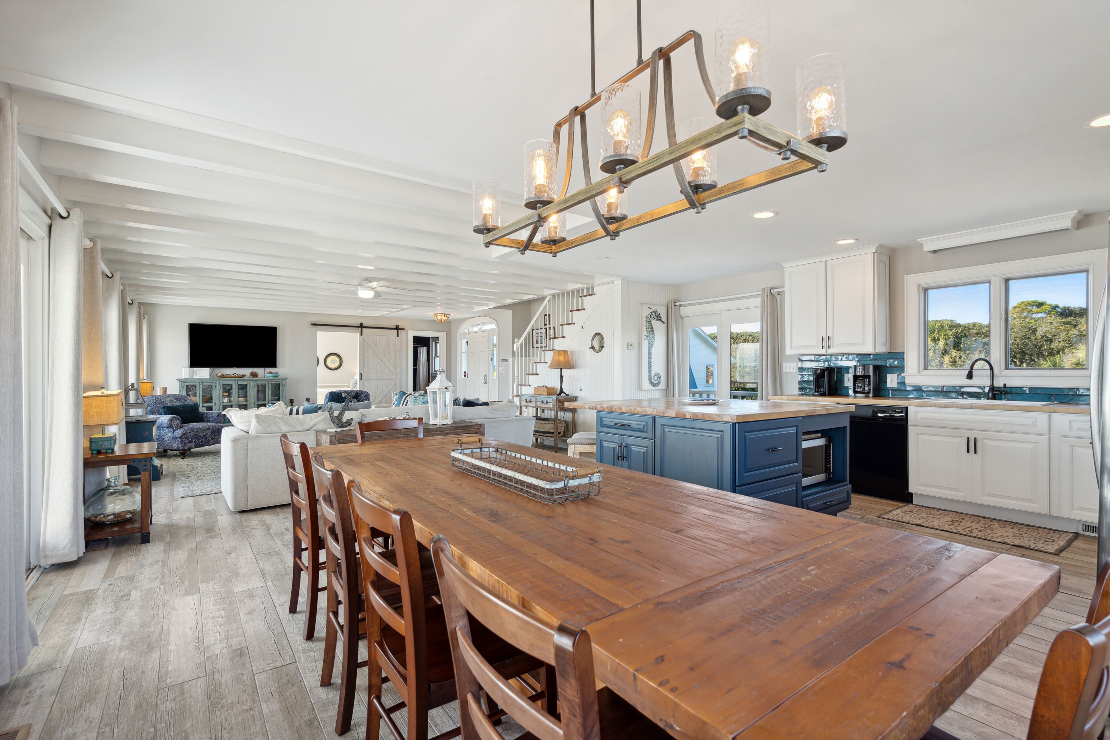Una cocina amplia con una mesa de comedor de madera, armarios azules y un ventanal con vistas al exterior.