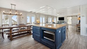 A spacious kitchen with a large island, wooden flooring, and a modern chandelier.