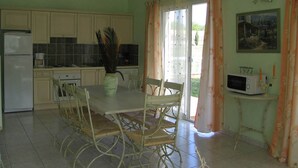 A kitchen with a dining table, chairs, a refrigerator, a microwave, and a window with curtains.