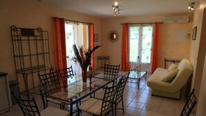Un coin repas avec une table et des chaises en verre, un canapé et un miroir au mur.
