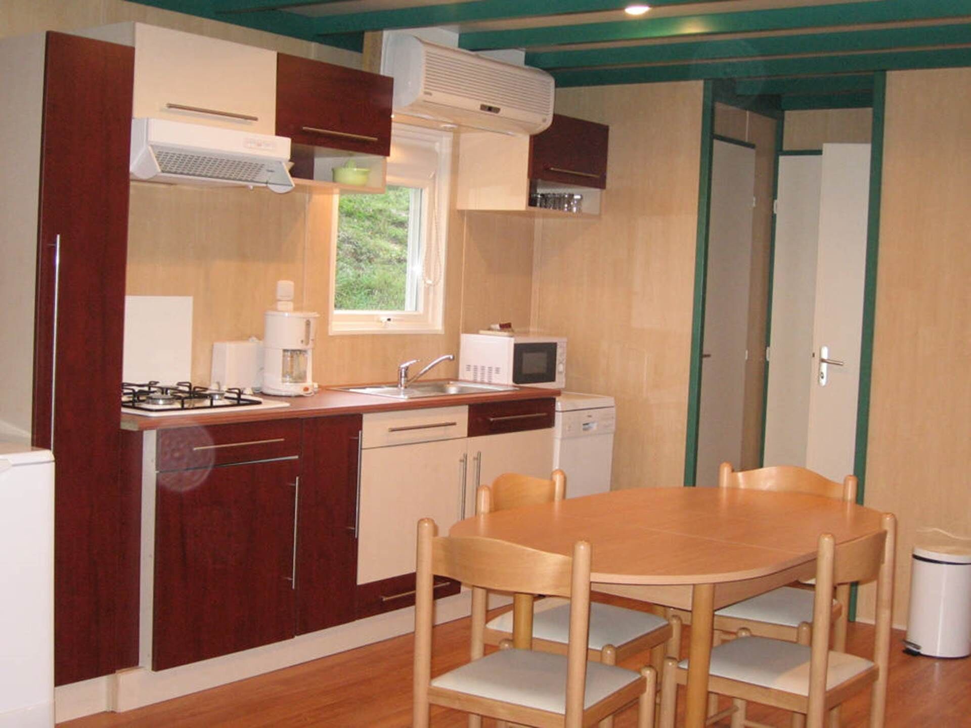 A compact kitchen with a gas stove, microwave, and dishwasher. There is a dining table with four chairs.