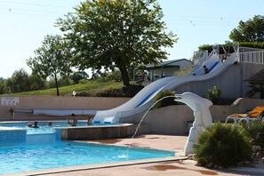 A swimming pool with a water slide and a lifeguard tower.