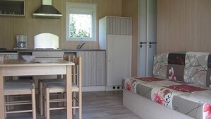 A compact living space with a kitchenette, a dining area, and a sofa. - Chalet 5 people (MONTREAL)