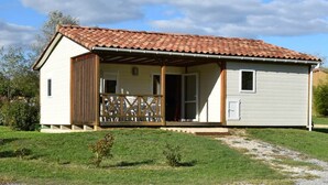Une maison de plain-pied avec un toit en tuiles, une véranda et un petit jardin devant.
