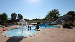 Une piscine dotée d’une fontaine, d’un toboggan et de chaises longues.