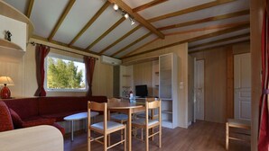 Une pièce chaleureuse avec un plafond en bois, une table à manger avec des chaises, un canapé rouge et un téléviseur.