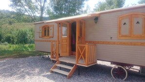 A mobile home with a porch, a door, and a window with a decorative frame.