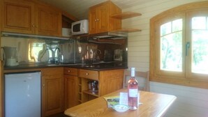 A compact kitchen with wooden cabinets, a microwave, a sink, and a small refrigerator.