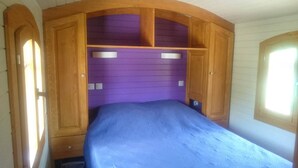 A bedroom with a bed, wooden cabinets, and a purple wall.