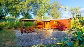 A vintage train car converted into a stationary structure with a covered picnic area and a dining table. - 4/5 people trailers (MONTREAL)