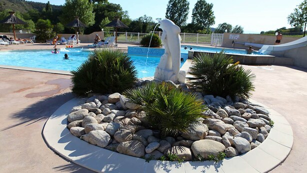A swimming pool with a statue, surrounded by rocks and plants. - 4/5 people trailers (MONTREAL)