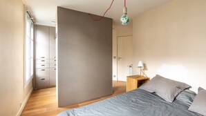 Une chambre à coucher avec un lit, une table de chevet, une lampe, une armoire et une porte.