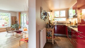 Une cuisine moderne avec des meubles de rangement rouges, une table en bois et une vue sur le jardin.
