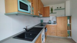 Una cucina con mobili in legno, un forno a microonde, un lavello, una lavatrice e una macchina per il caffè.
