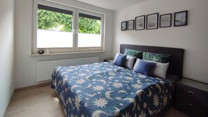 Una camera da letto con un letto, una finestra, un termosifone e quadri appesi al muro.