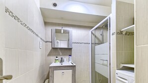 Un baño moderno con lavamanos, espejo y ducha.
