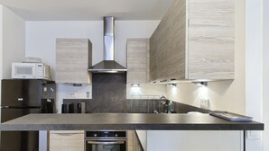 Una cocina moderna con una isla grande, electrodomésticos de acero inoxidable y paneles de madera en los armarios.