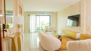 A modern living room with a sofa, a TV, and a dining area with chairs and a table. - The Six Apparthotel (Abidjan)