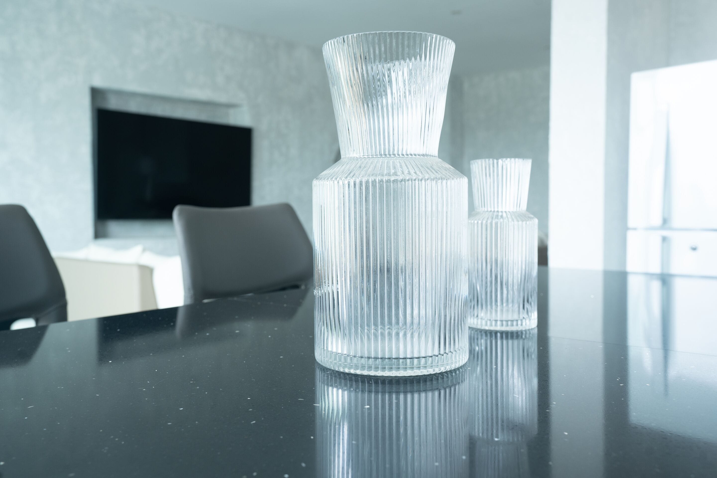 A glass vase on a reflective surface in a modern interior setting.