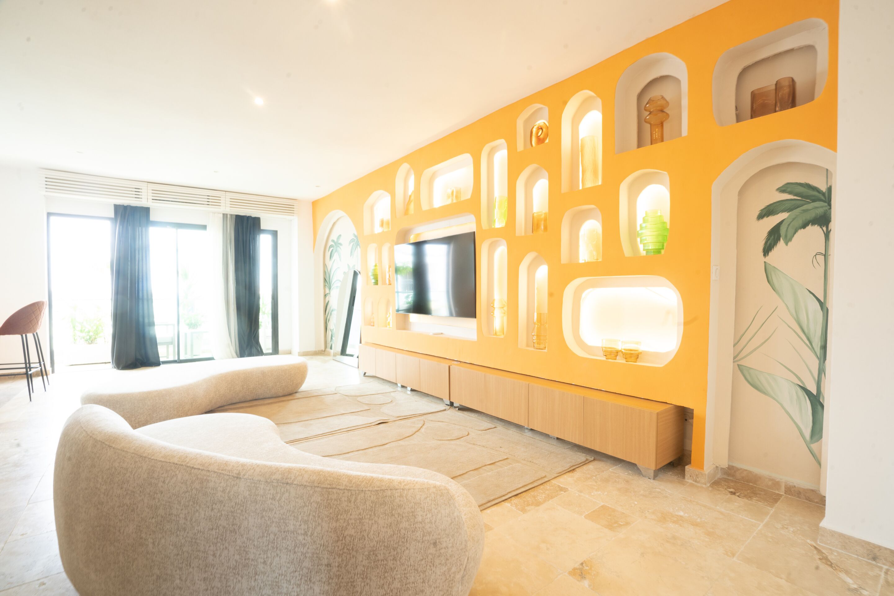 Ein modernes Wohnzimmer mit einem großen Flachbildfernseher, einer Couch und einem Essbereich mit gelber Akzentwand.