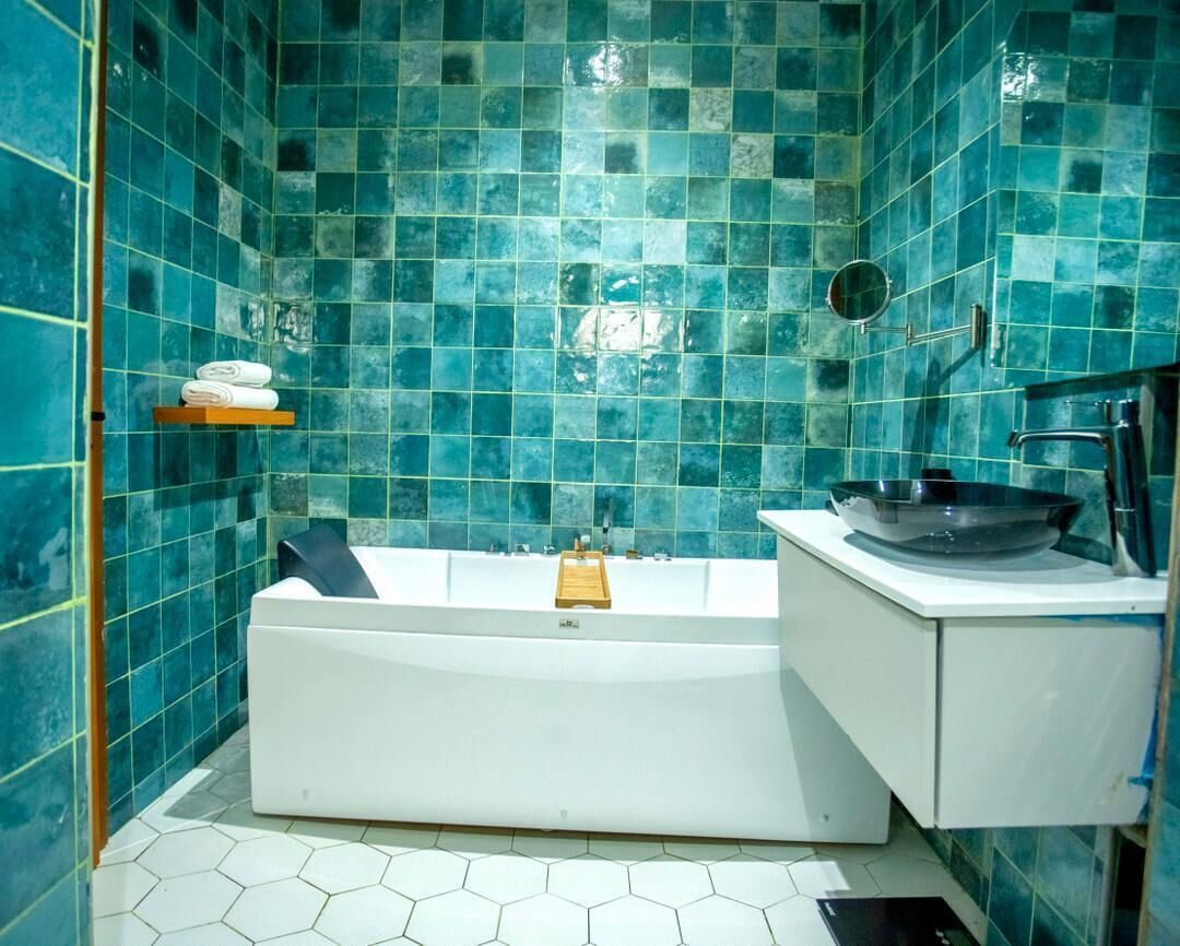A bathroom with a white bathtub, a sink with a bowl, and a shelf with towels.