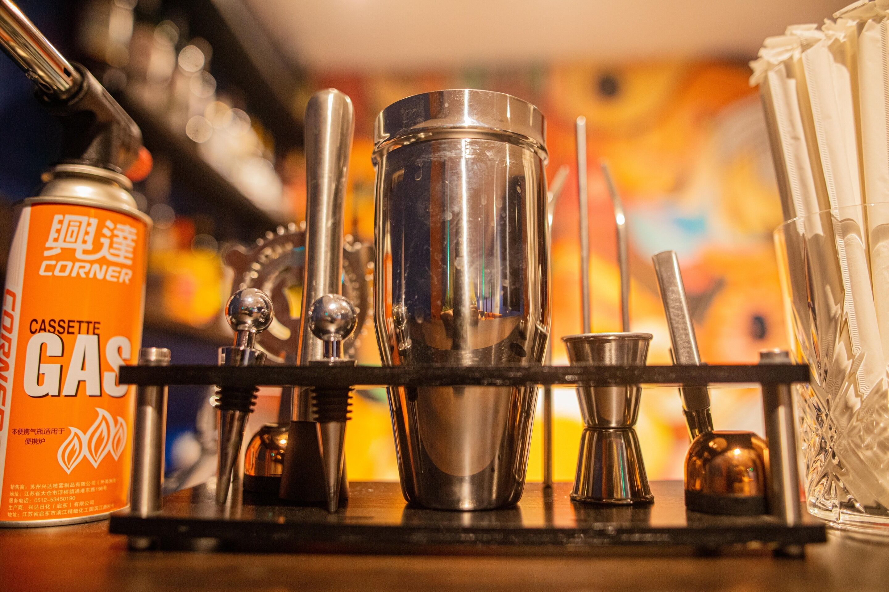 A bar setup with a metal shaker, a glass, and a can of beer.