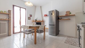 A modern kitchen with a dining table, chairs, a refrigerator, and a hanging light fixture. - Italian Experience - Il Colle Sul Mare Holiday Home (Porto Recanati)
