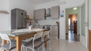 A modern kitchen with a granite countertop, stainless steel appliances, and a dining area with a table and chairs. - Italian Experience - Il Colle Sul Mare Holiday Home (Porto Recanati)