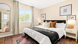 A modern bedroom with a large bed, a mirror, a window with curtains, and two bedside tables with lamps. - Brand New! Lower Flat 1BR Near Downtown, Roseville (Roseville)