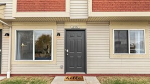 A two-story building with a beige exterior, a dark gray door, and two windows on the ground floor. - Brand New! Lower Flat 1BR Near Downtown, Roseville (Roseville)
